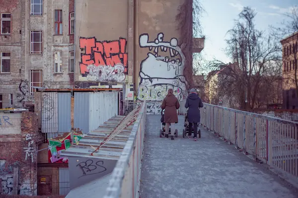 Zwei Frauen gehen auf einer mit Graffiti bedeckten Brücke