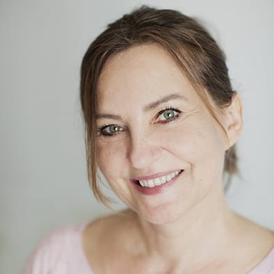 Eine lächelnde Frau mittleren Alters mit schulterlangem braunem Haar.